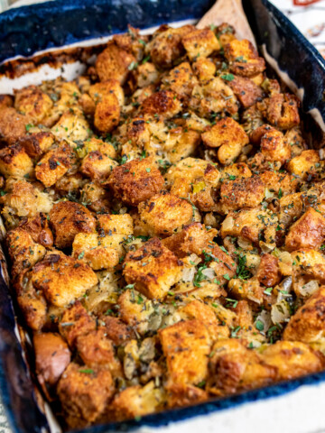 classic Thanksgiving stuffing in a blue and white baking dish with a wooden spoon