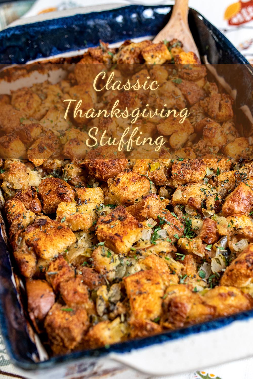 classic Thanksgiving stuffing in a blue and white baking dish with a wooden spoon