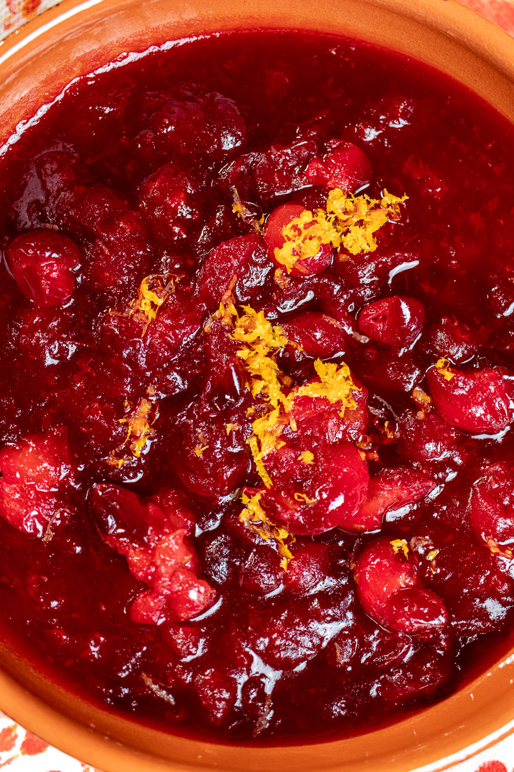 close up of cranberry sauce with orange zest on top in an orange bowl