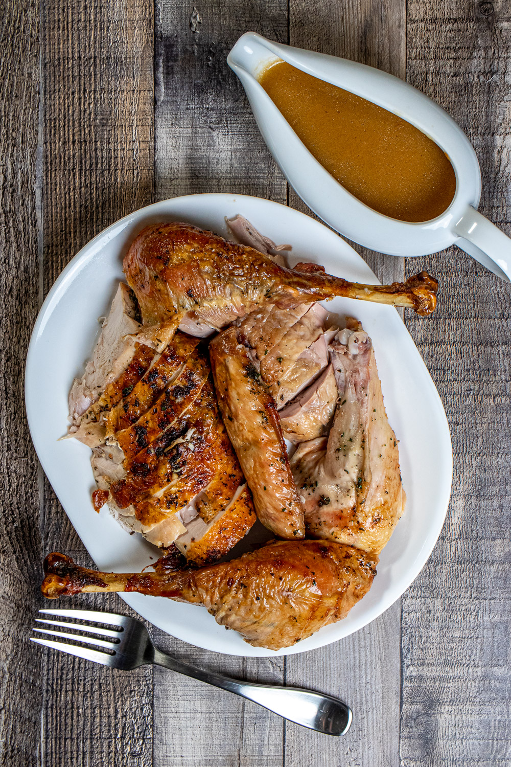 herb-roasted turkey and gravy carved on a white serving platter