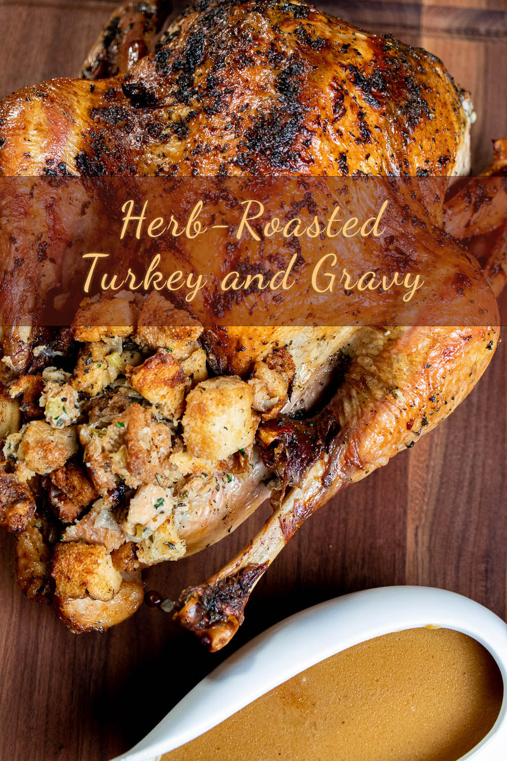 whole herb roasted turkey with stuffing and side of gravy on a wooden cutting board