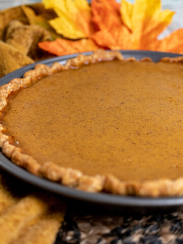 classic pumpkin pie with fall decorations around it