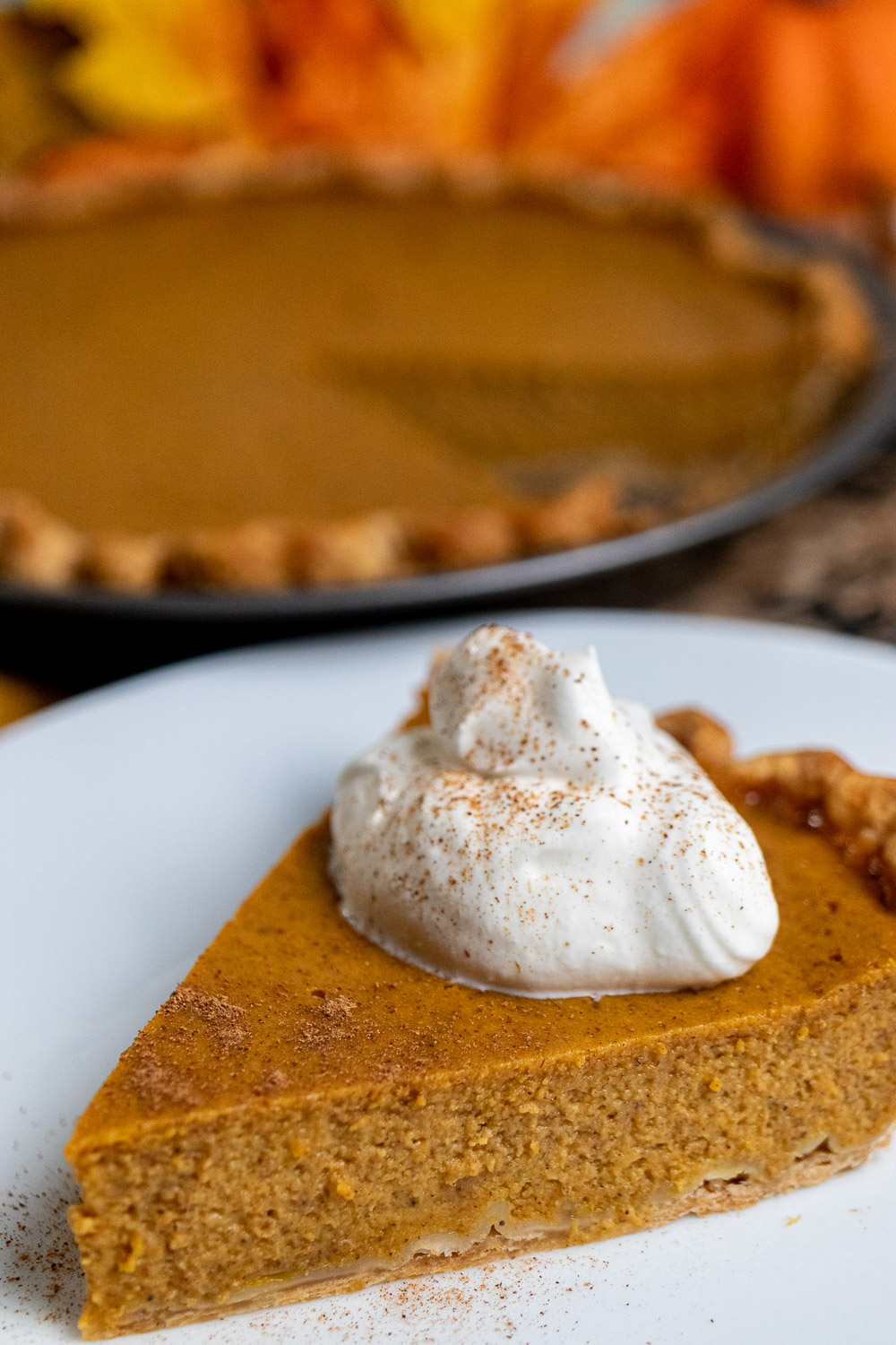 close up of a slice of classic pumpkin pie on a white plate
