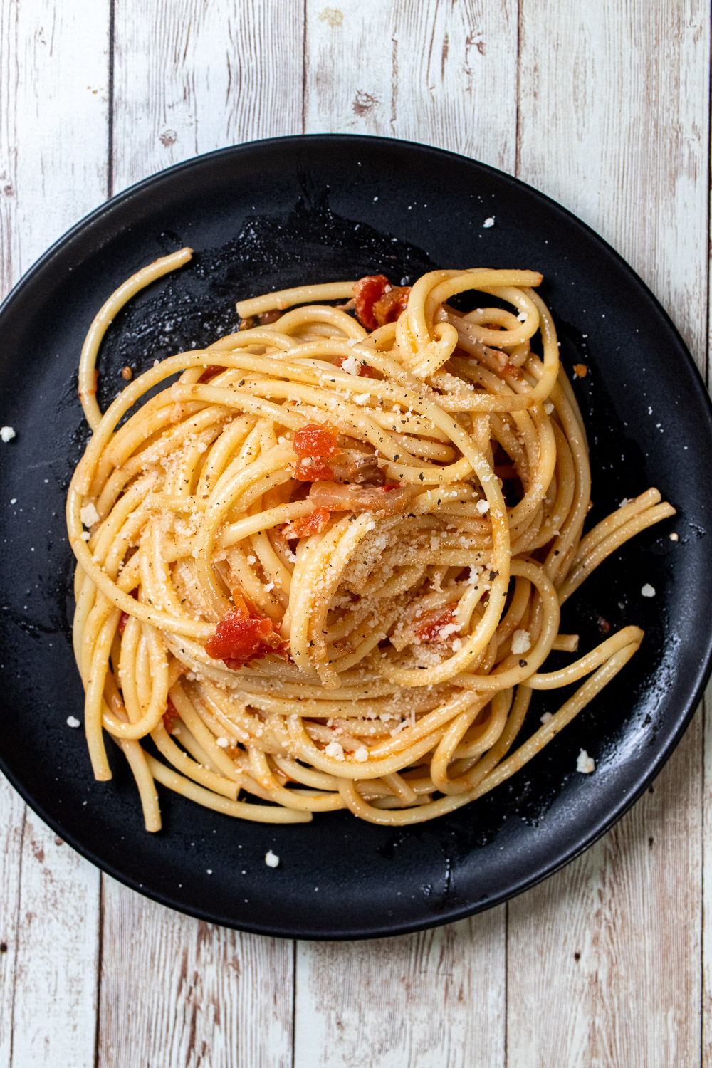 Authentic bucatini all'amatriciana served on a black plate.