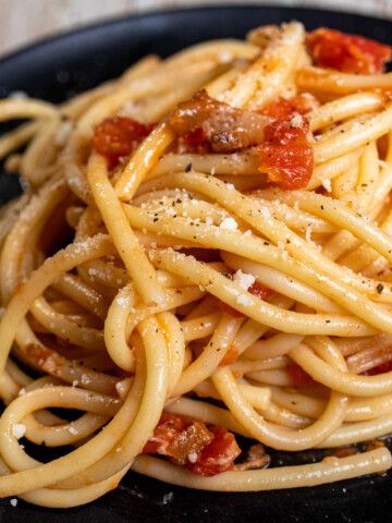 Authentic bucatini all'amatriciana served on a black plate.