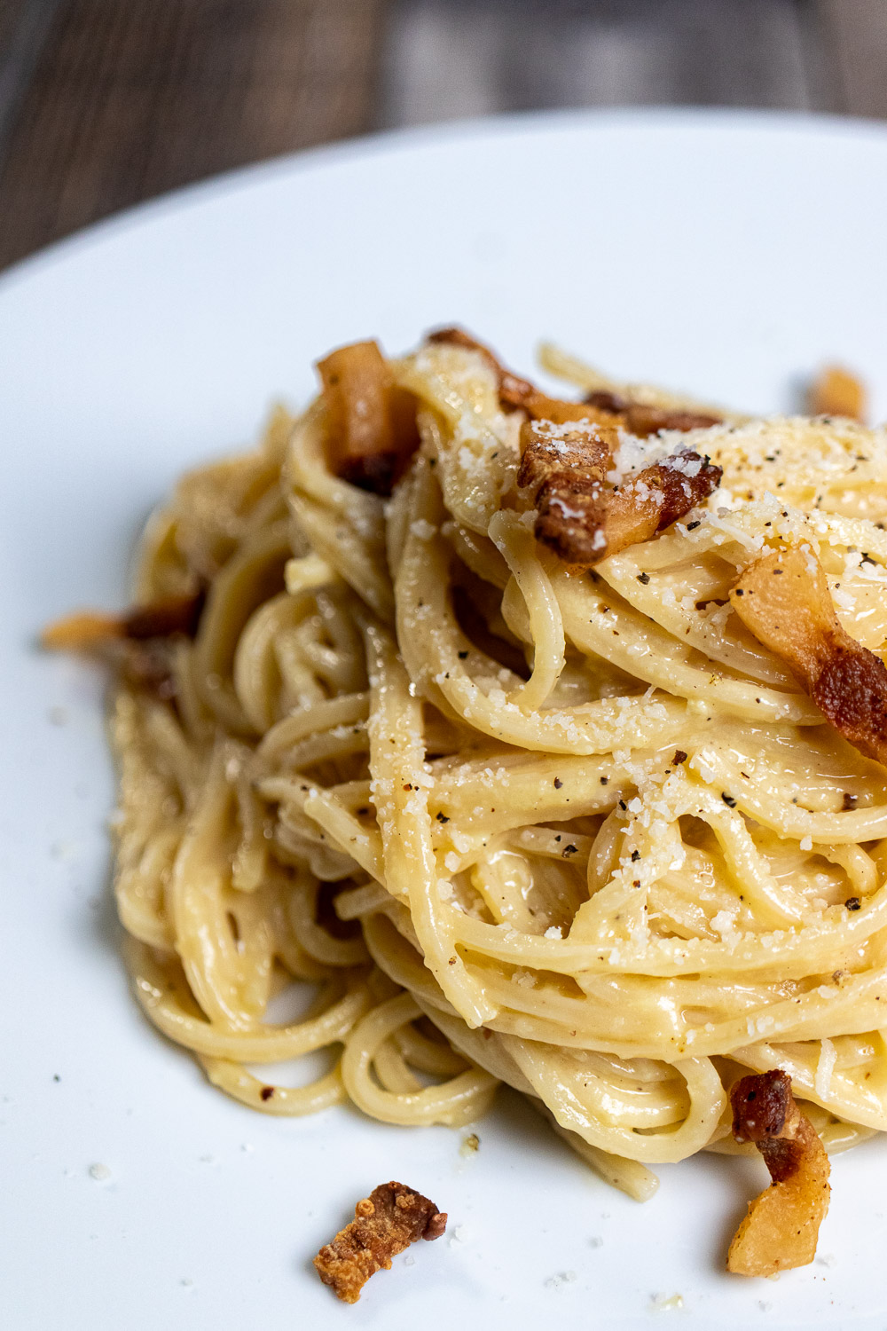 Authentic spaghetti carbonara made with guanciale and Pecorino Romano cheese on a white plate.