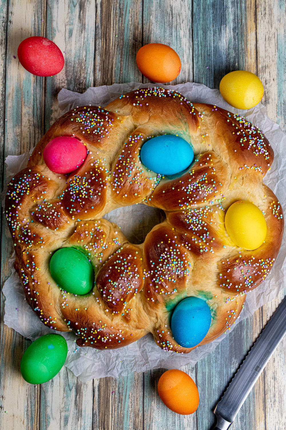 Overhead view of braided Italian Easter bread with dyed eggs and sprinkles