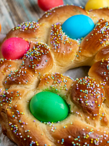 close up view of braided Italian Easter bread with dyed eggs and sprinkles