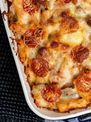 Overhead view of baked rigatoni with Italian sausage and meatballs in a large, blue baking dish.