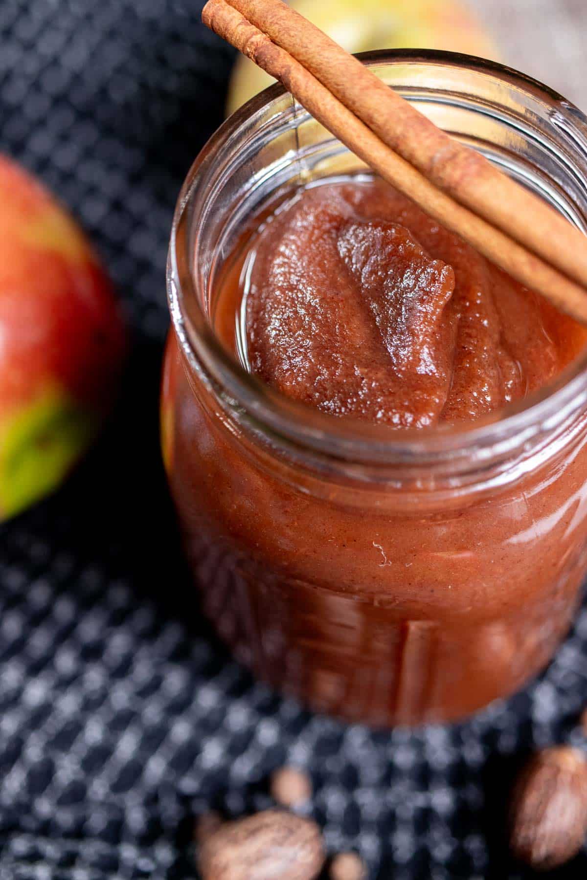 Overhead view of a pint jar full of apple butter with a cinnamon stick across the top. 
