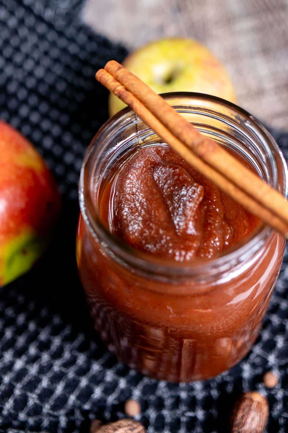 Overhead view of a pint jar full of apple butter with a cinnamon stick across the top.