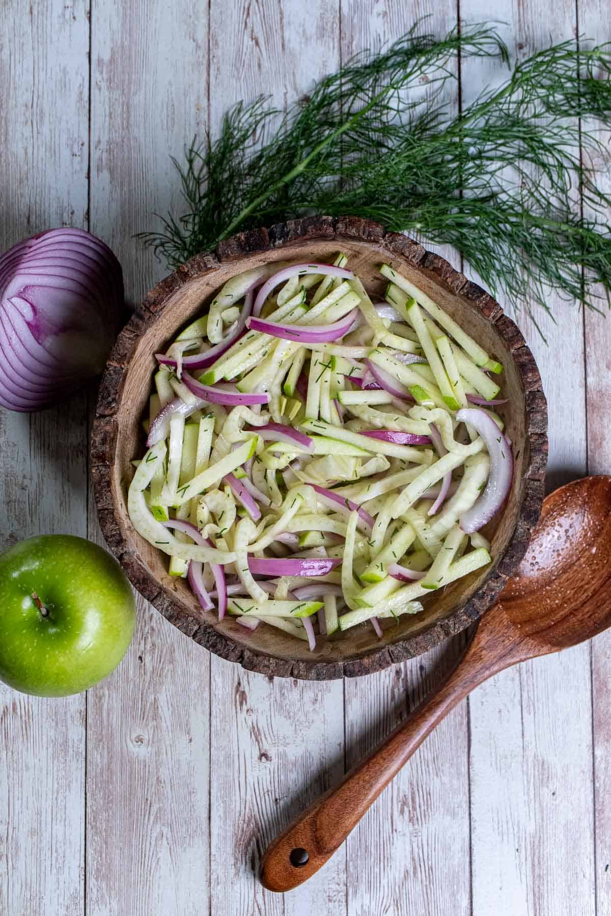 Overhead view of fennel and apple slaw in a wooden bowl.