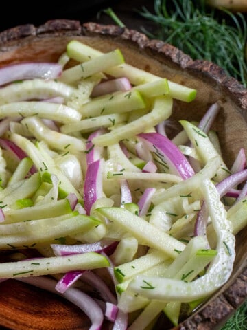 Close up view of fennel apple slaw in a wooden bowl.