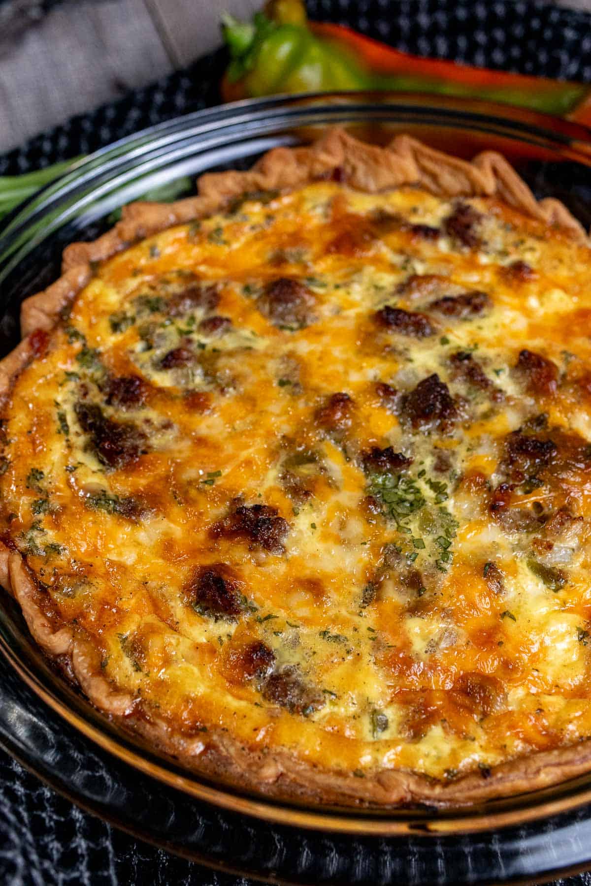 Angled view of green chile sausage quiche in a glass pie plate.