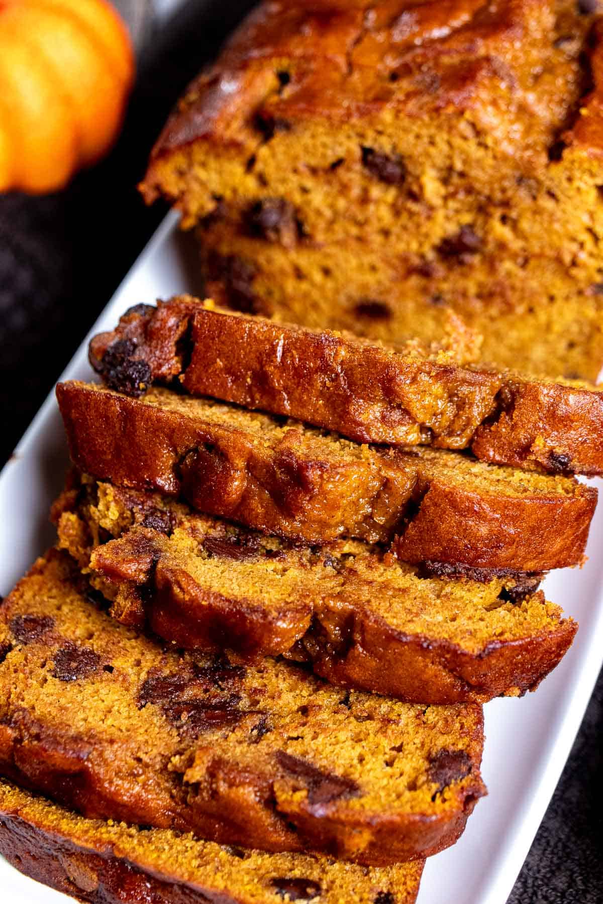 Angled view of sliced chocolate chip pumpkin bread on a white plate.