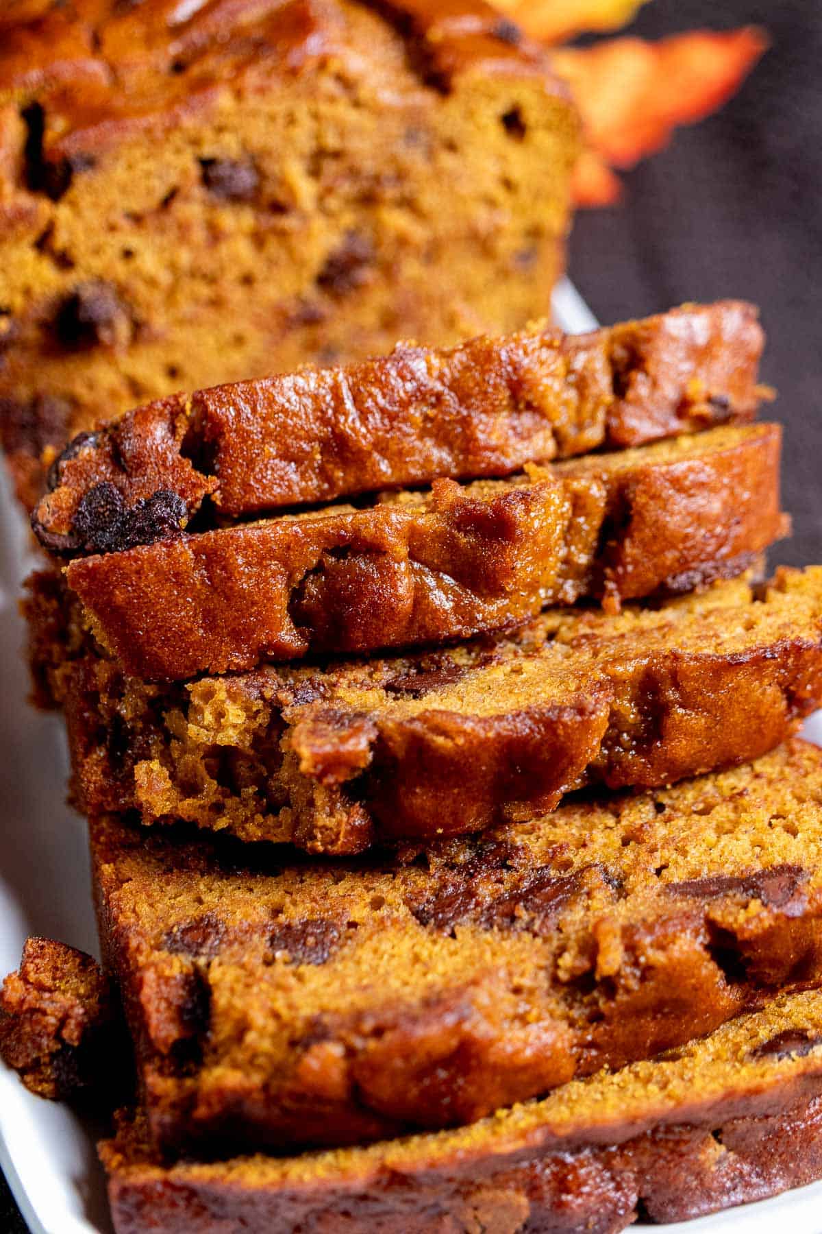 Close up view of sliced chocolate chip pumpkin bread on a white plate.