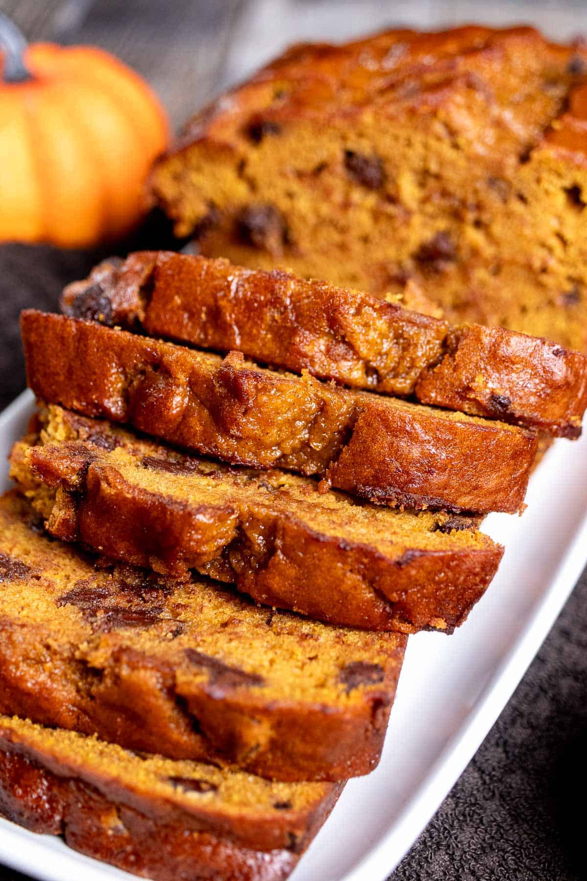 Close up view of sliced chocolate chip pumpkin bread on a white plate.