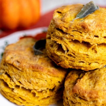 Close up of pumpkin sage biscuits stacked on a white plate.