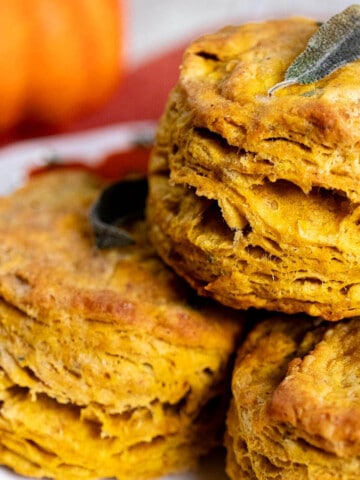 Close up of pumpkin sage biscuits stacked on a white plate.