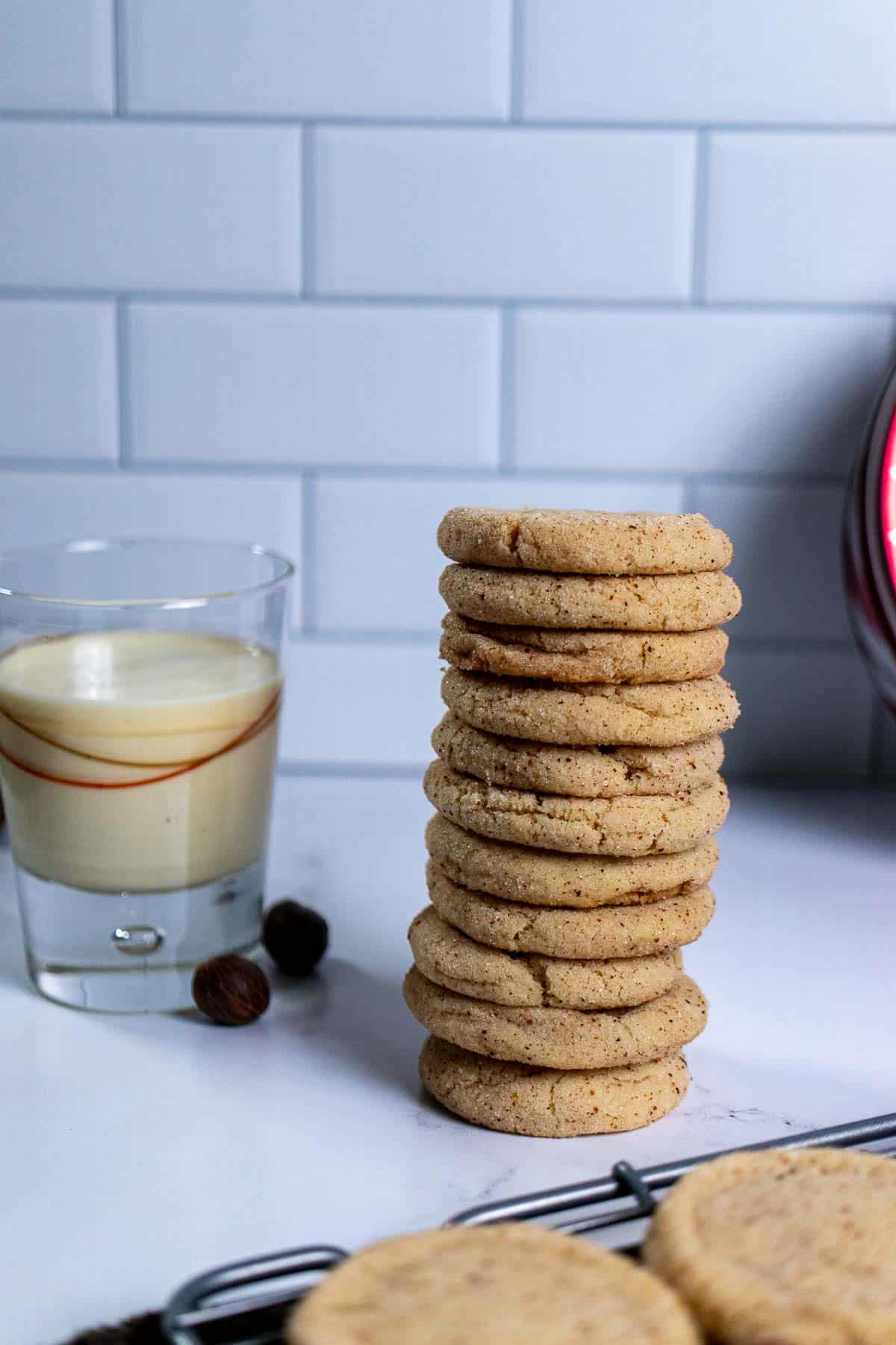 A stack of eggnog snickerdoodles with a glass of eggnog beside them.