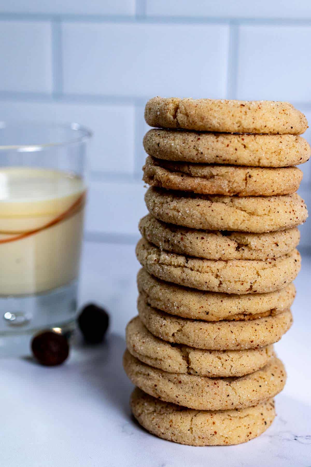 Closer view of a stack of eggnog snickerdoodle cookies with a glass of eggnog beside them.