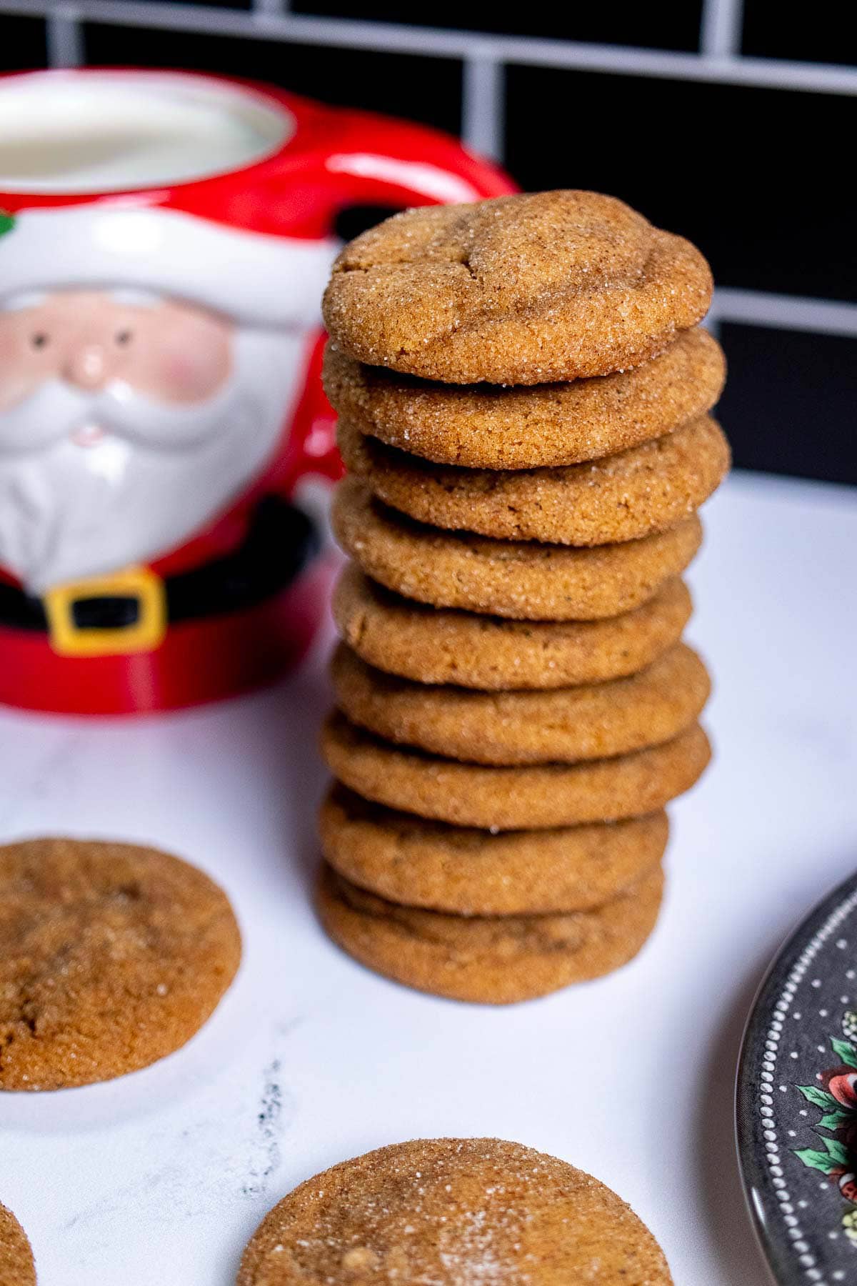 A stack of gingerbread snickerdoodles next to a Santa mug with milk in it.