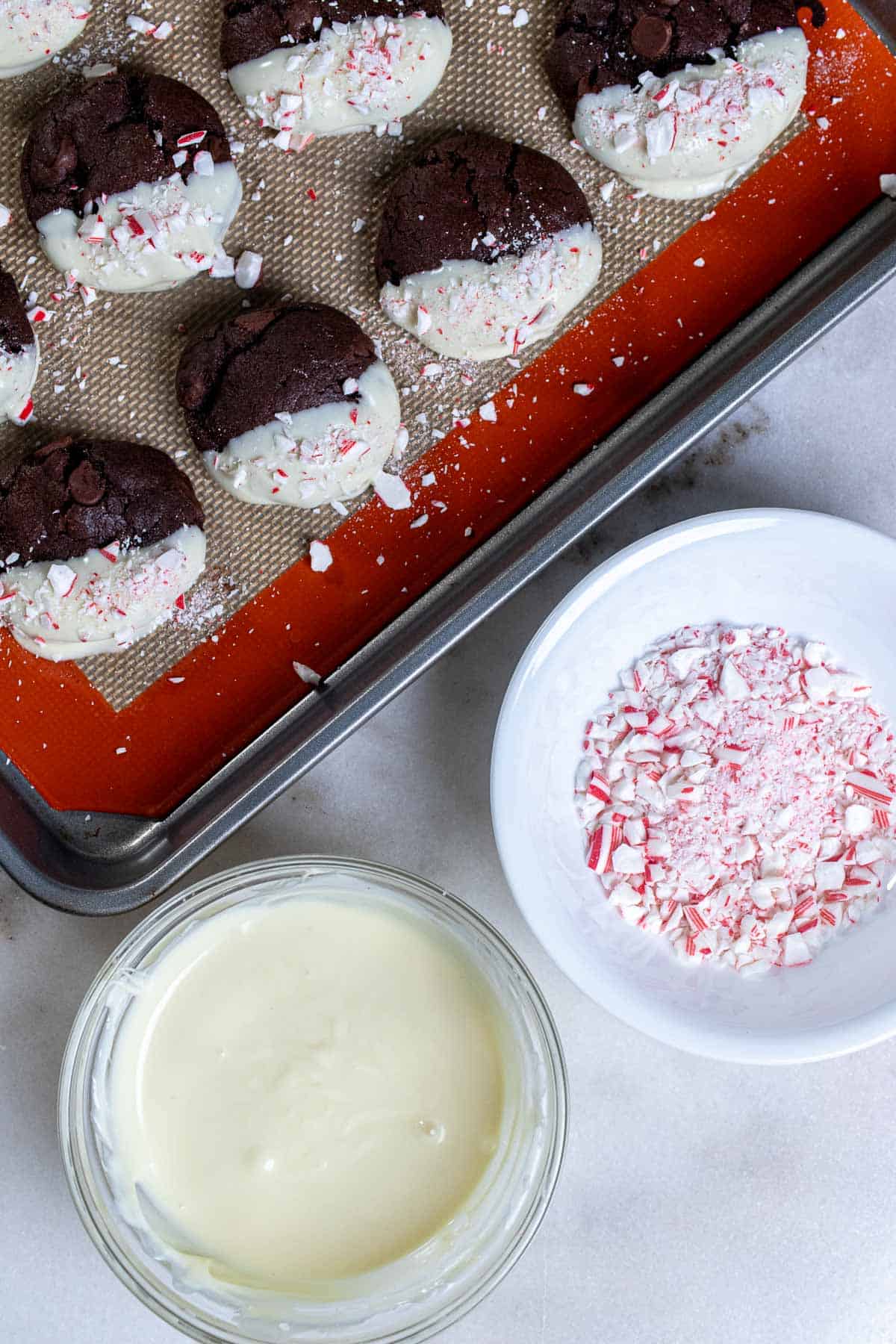 Dipping mocha cookies into melted white chocolate and sprinkling with crushed candy canes.