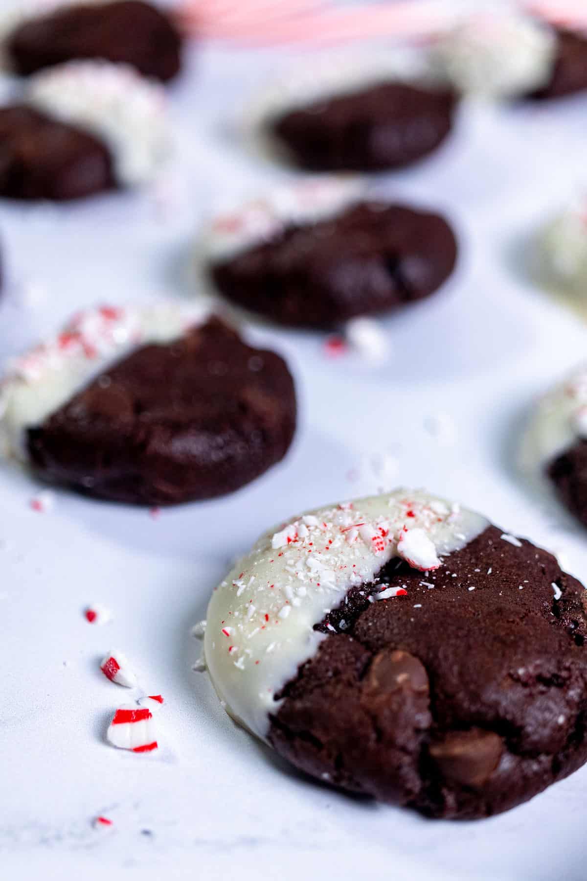 Close up of peppermint mocha cookies on marble with small pieces of candy canes spread around.
