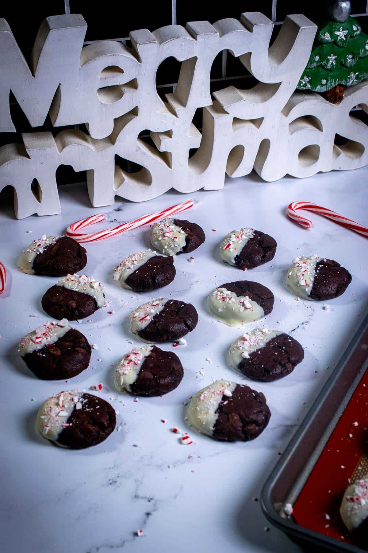 White chocolate peppermint cookies on marble in front of a Christmas sign.