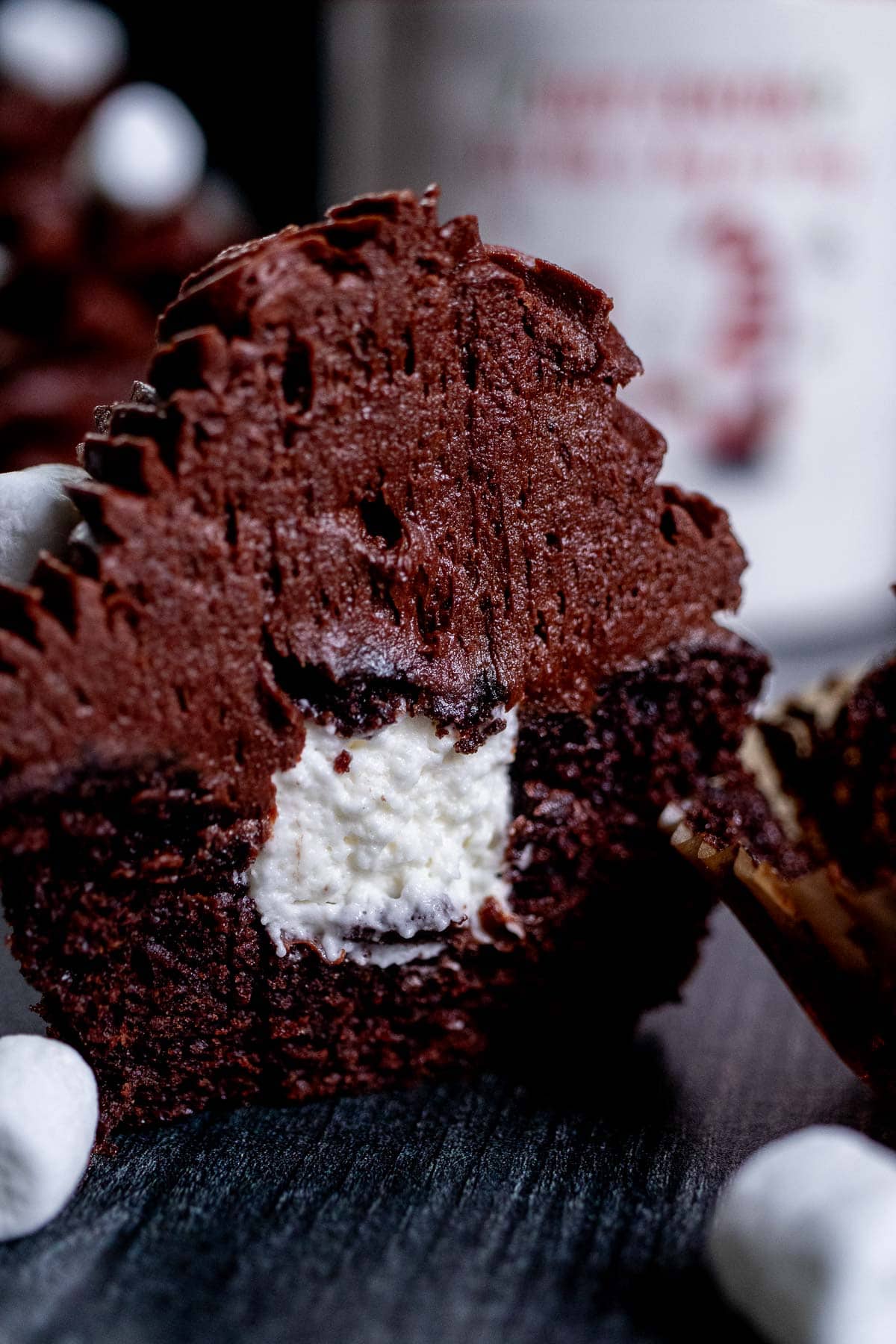 Close up view of a hot cocoa cupcake cut in half to see the marshmallow filling on the inside.