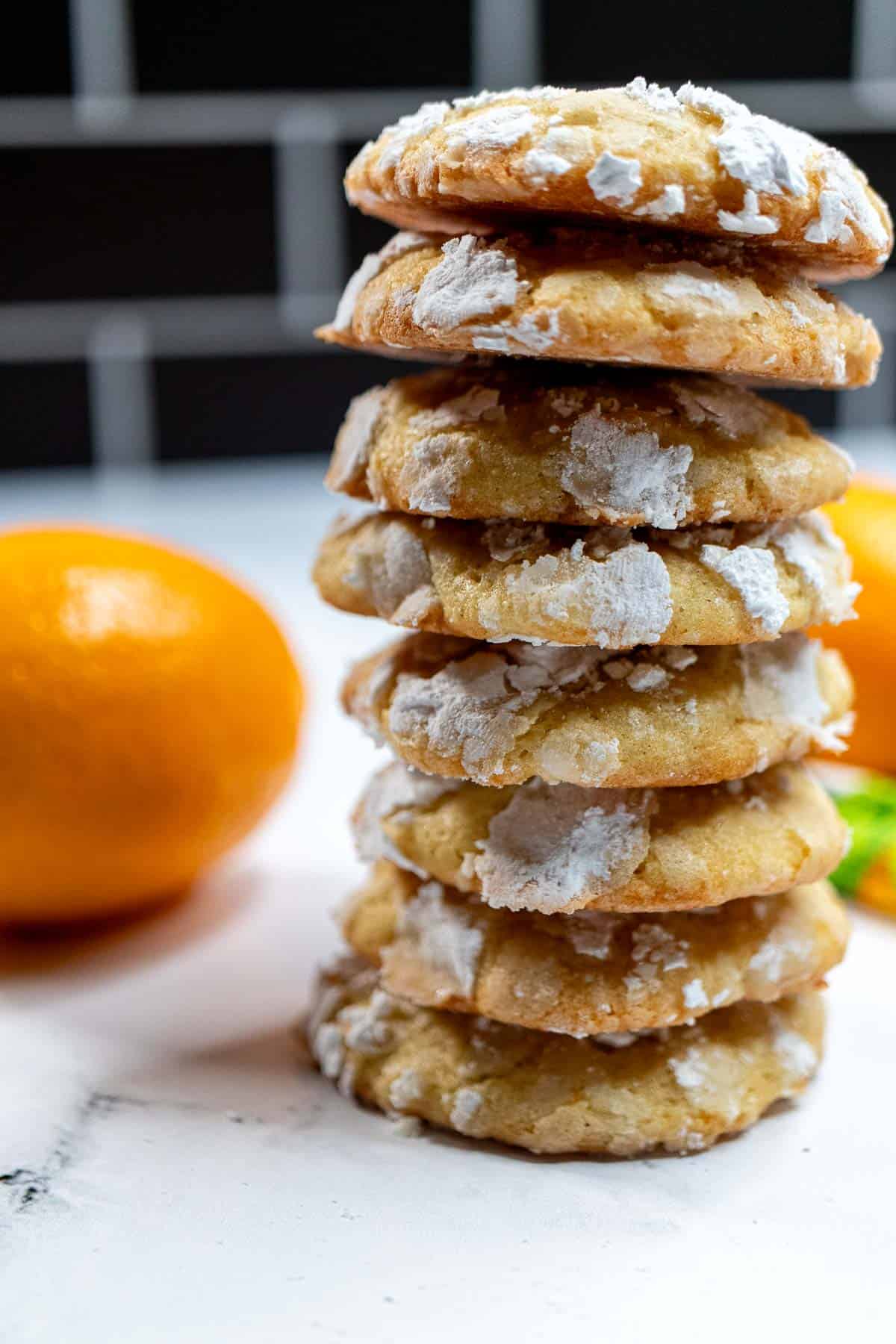 Stack of Meyer lemon crinkle cookies with a Meyer lemon to the left of them.