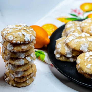 A plate of Meyer lemon crinkles with a stack of cookies next to it.
