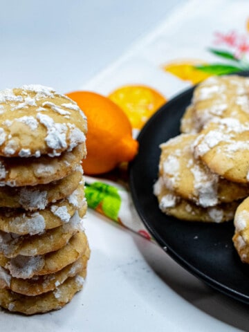 A plate of Meyer lemon crinkles with a stack of cookies next to it.