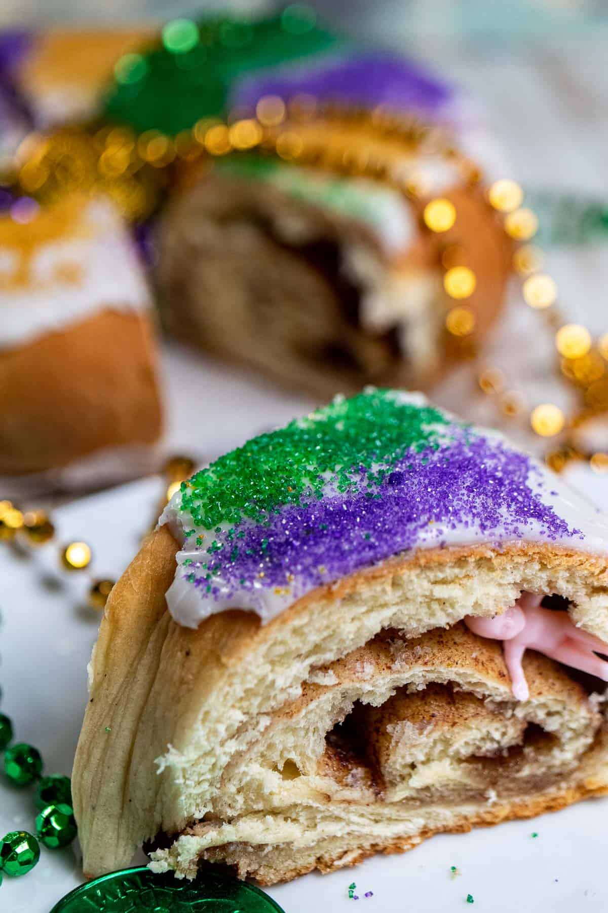 Close up of a slice of king cake with a plastic baby inside.