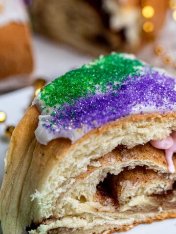 Close up of a slice of king cake with a plastic baby inside.