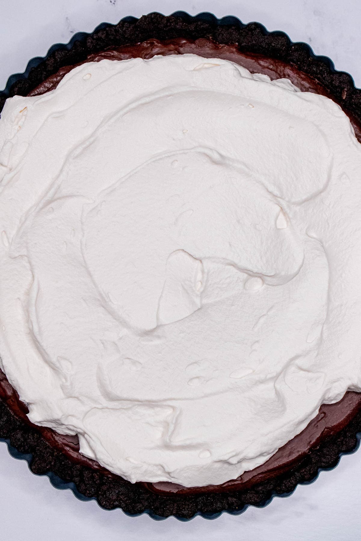 A dark chocolate tart topped with whipped cream.