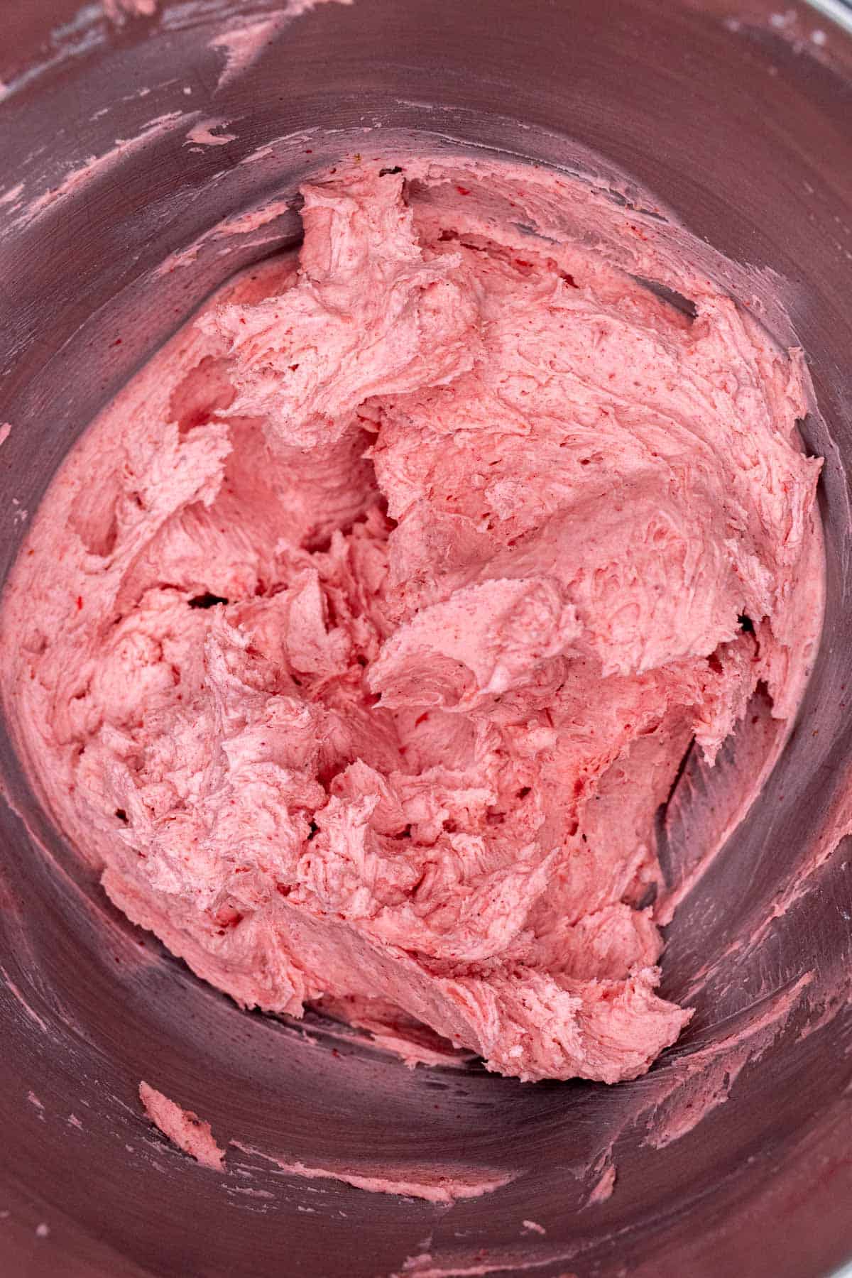 Strawberry buttercream in bowl of stand mixer after heavy cream was added and beaten until fluffy.