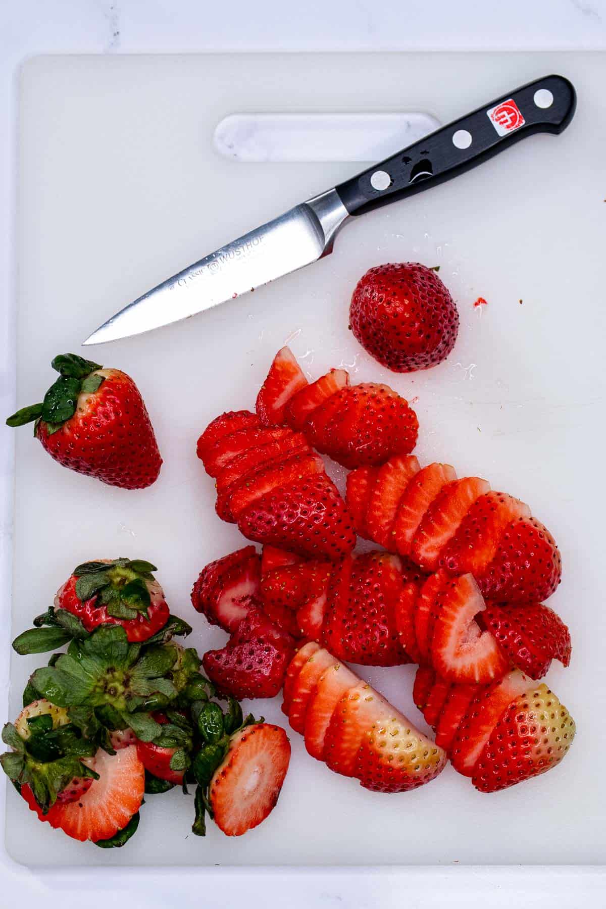 Trimming and slicing strawberries with a paring knife.