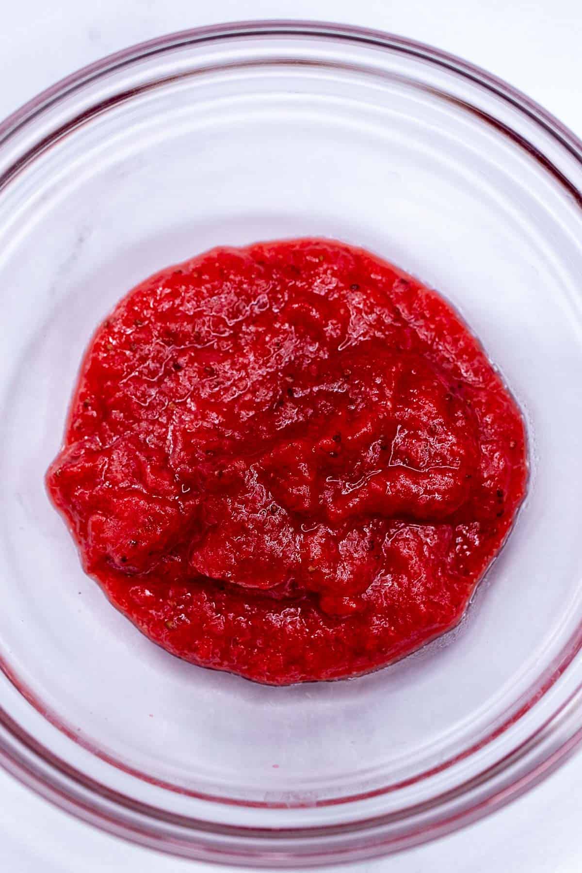 Strawberry puree reduced on stovetop in a heatproof bowl.