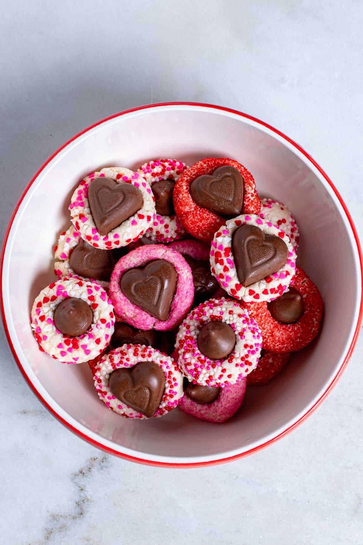 Overhead view of red and pink Valentine cream cheese blossom cookies in a bowl.