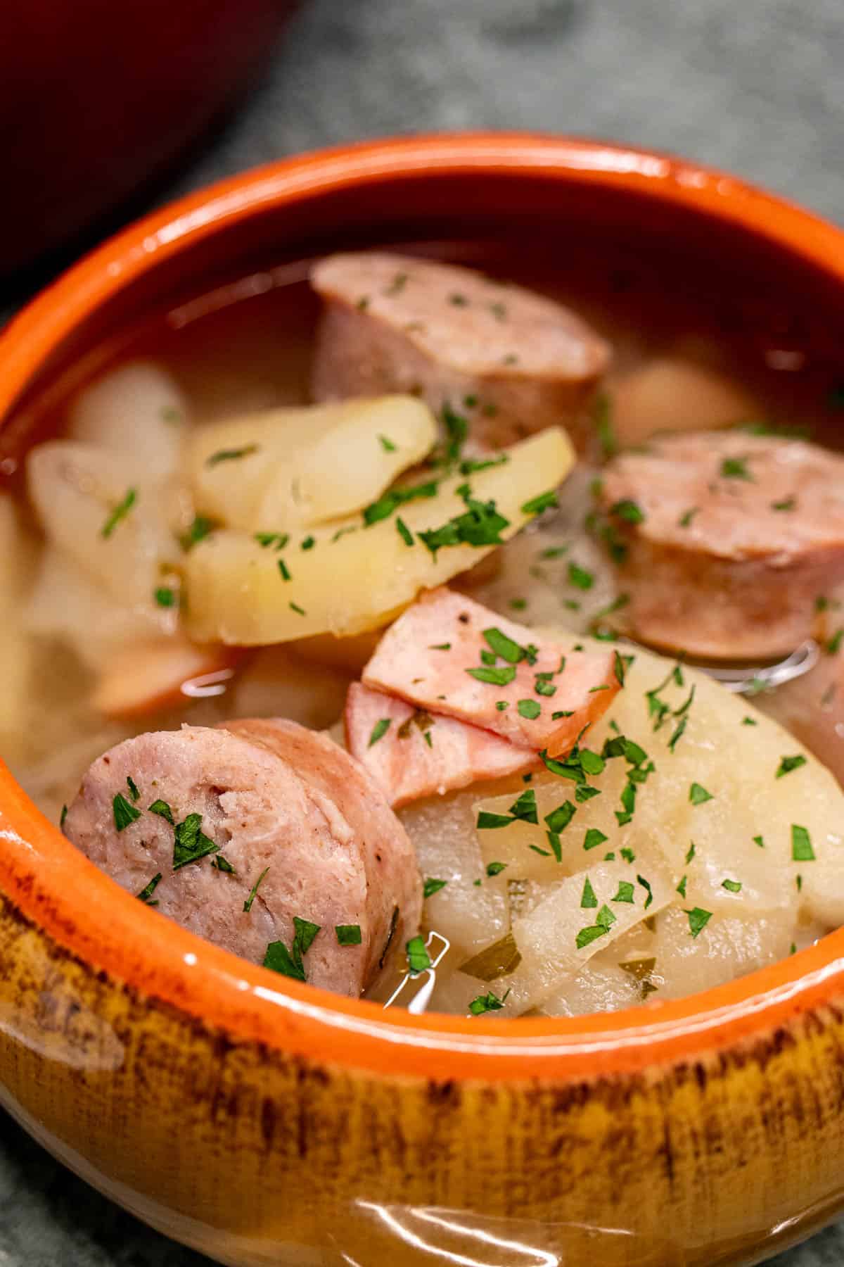 Close up view of a bowl of Irish coddle with sausages and potatoes.