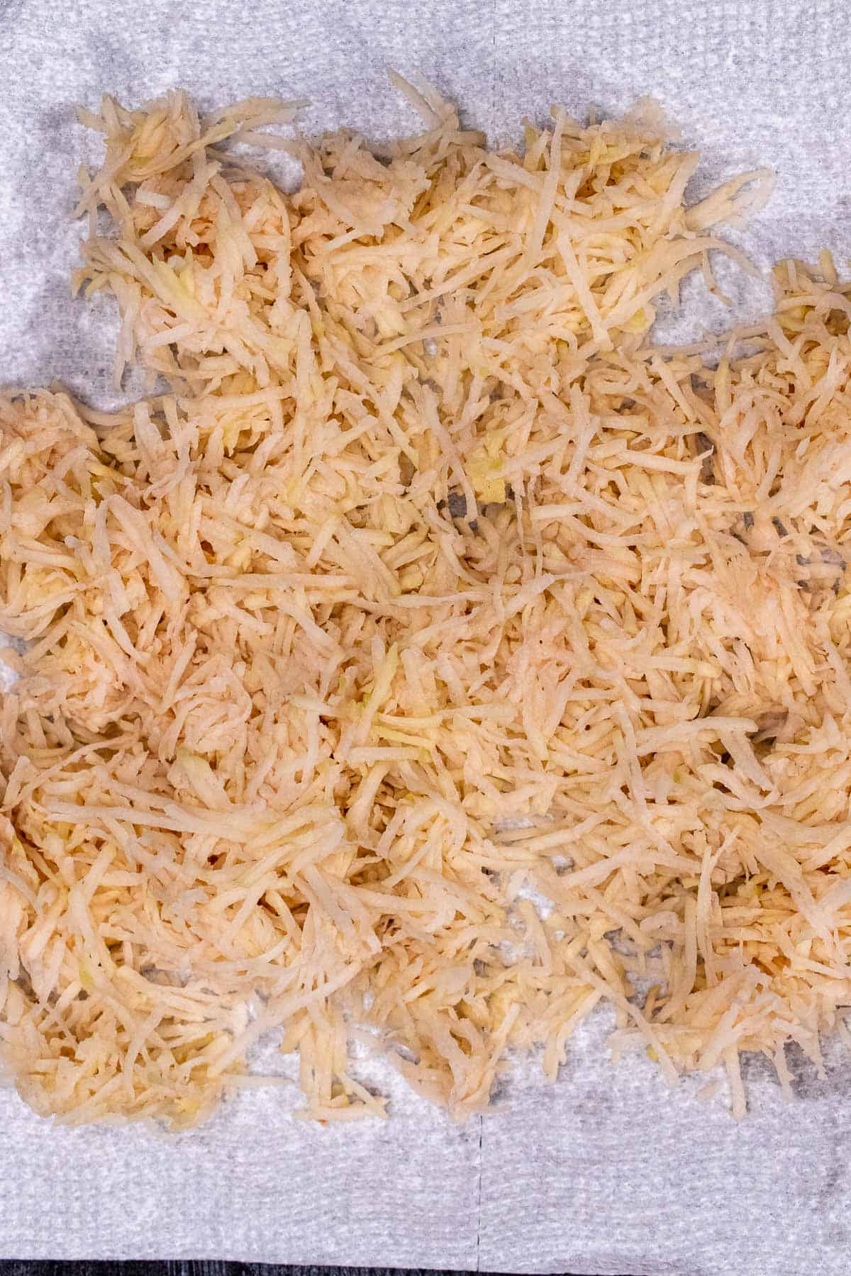 Peeled and shredded potatoes drained of excess moisture on a paper towel.