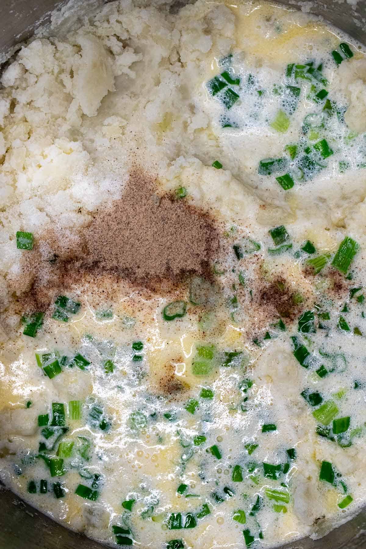 Salt, pepper, and scallion milk mixture added to mashed potatoes.