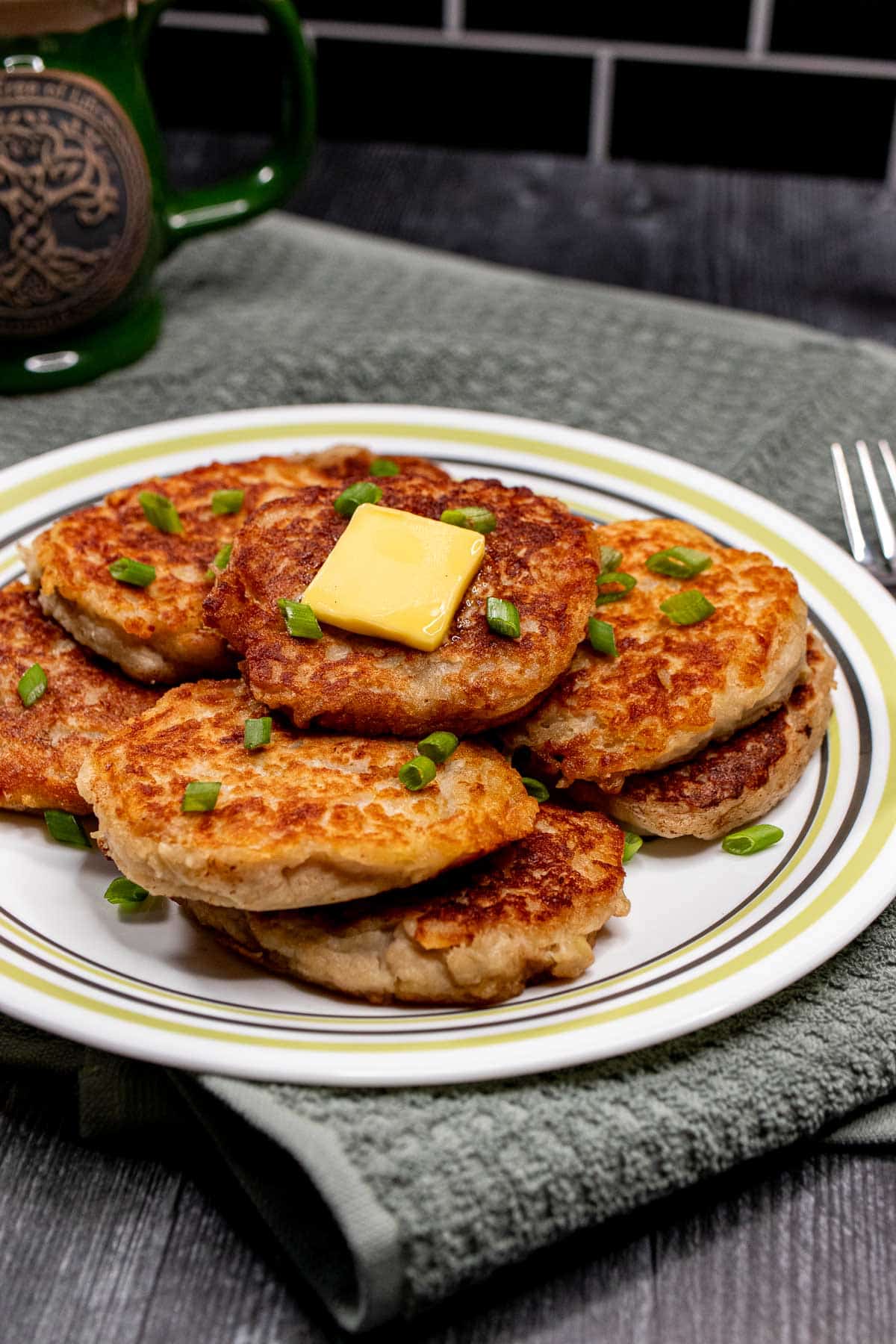 Plate of Irish potato pancakes with a green teacup behind them.