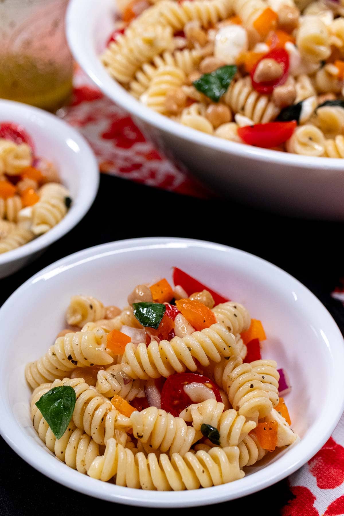Closer view of a side bowl of pasta salad with more bowls behind it.