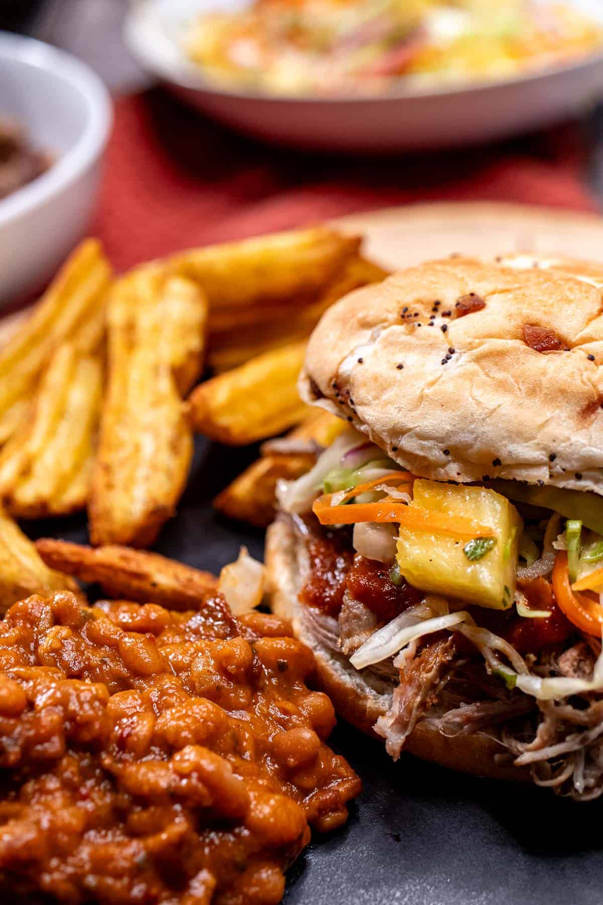 Guinness pulled pork sandwich with fries, smoky BBQ baked beans, and topped with spicy pineapple slaw.
