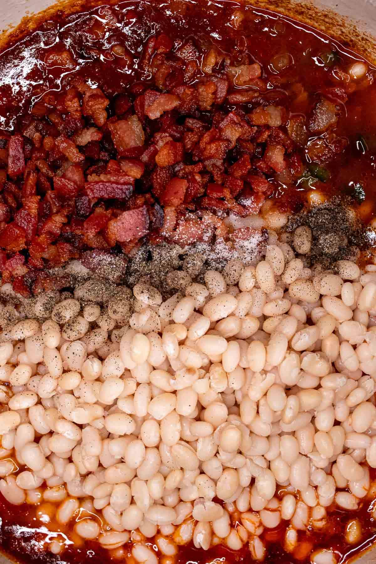 Adding the navy beans and reserved bacon into the Dutch oven.