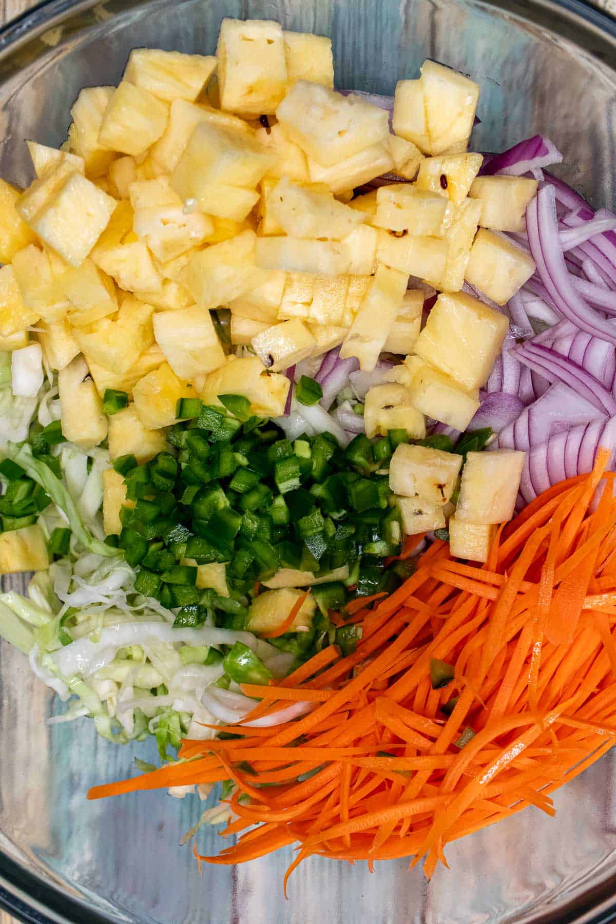 Spicy pineapple slaw ingredients in a glass bowl.