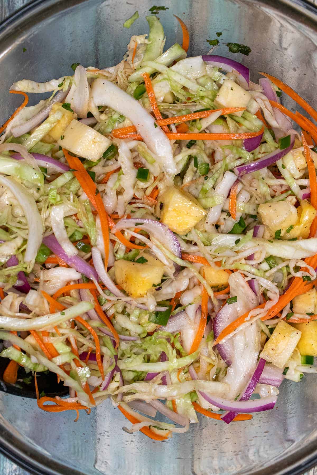 Pineapple slaw tossed with lime and mint dressing in a glass mixing bowl.