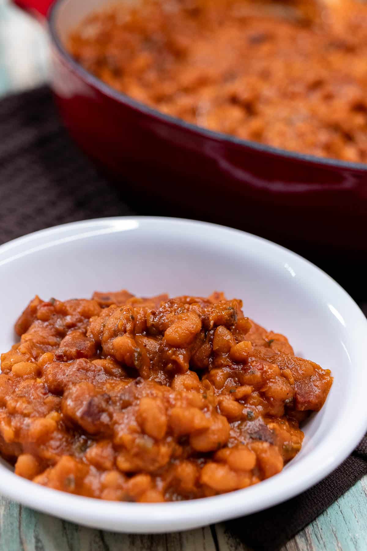A small white dish of smoky BBQ baked beans.